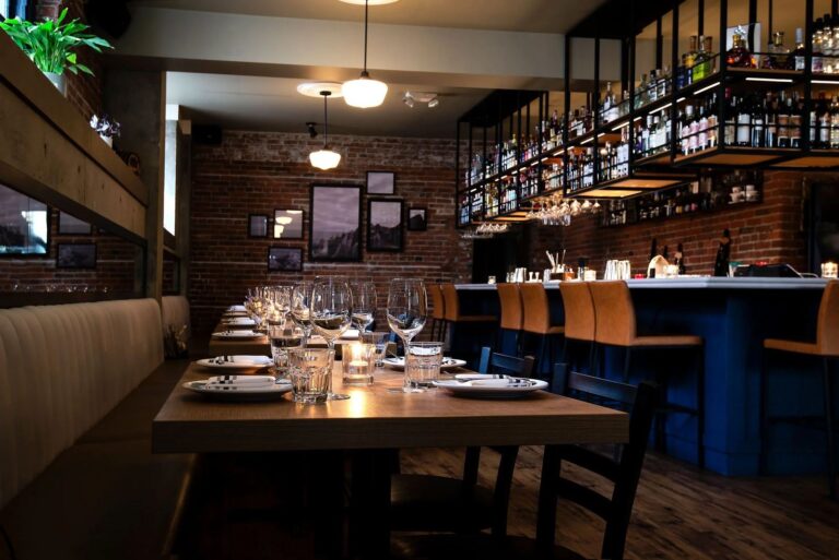 The dining room seen end to end, banquette seating along one wall and tables set for service