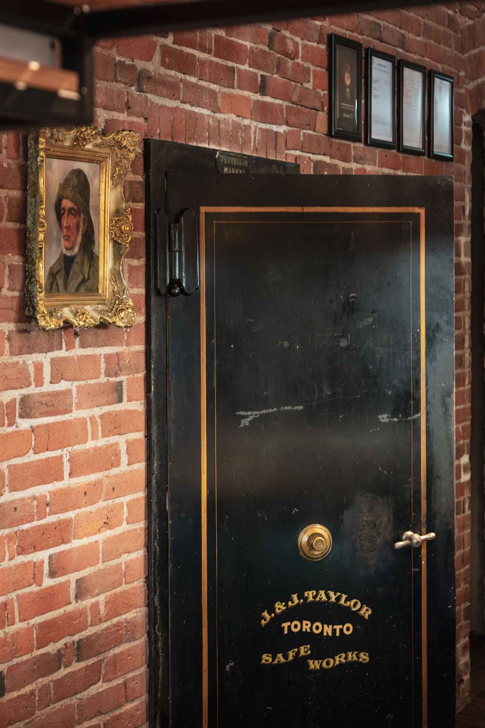 The entrance, an old safe-works door set into the building's red brick facade
