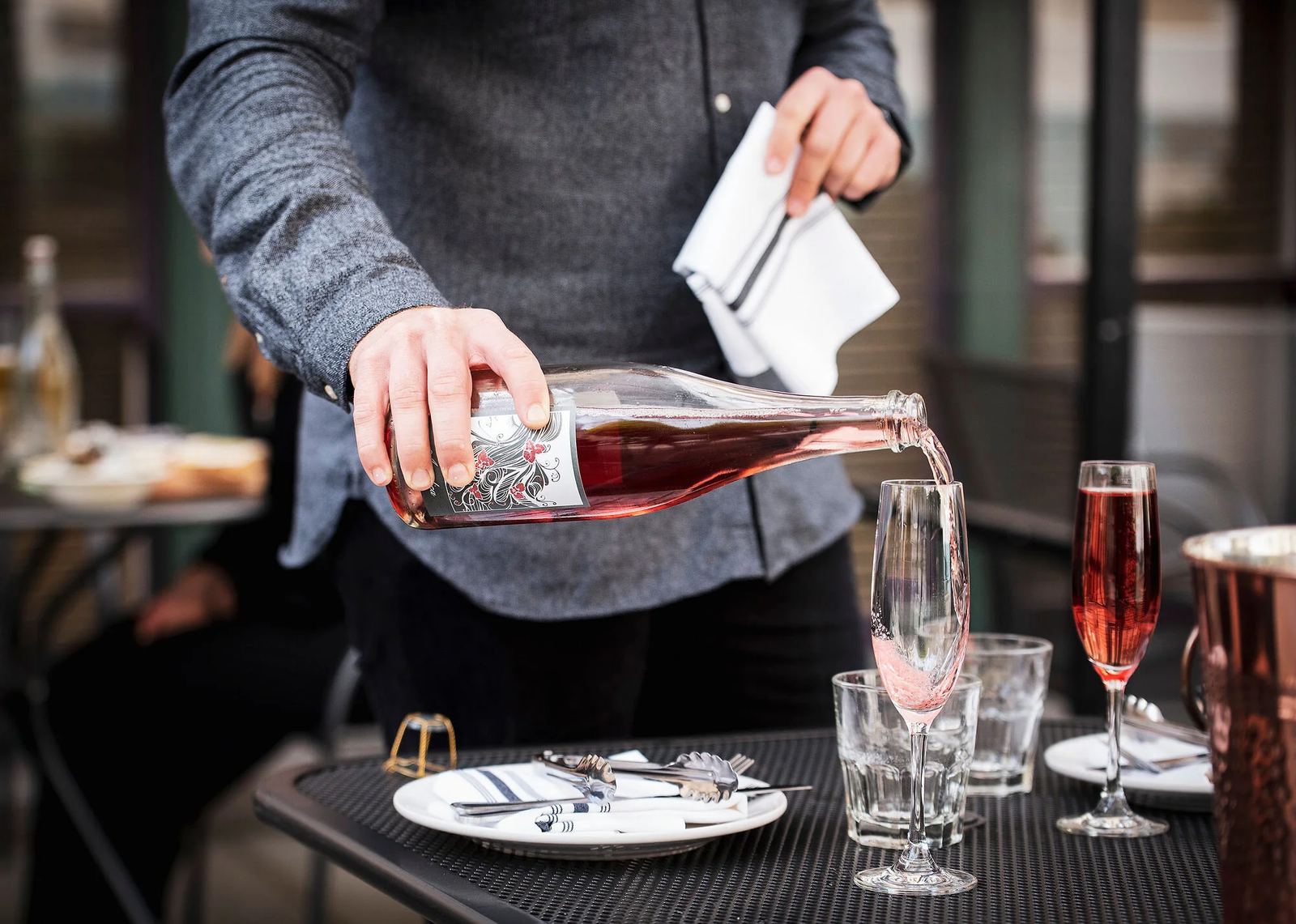 A server pouring red wine into a glass at a candlelit table