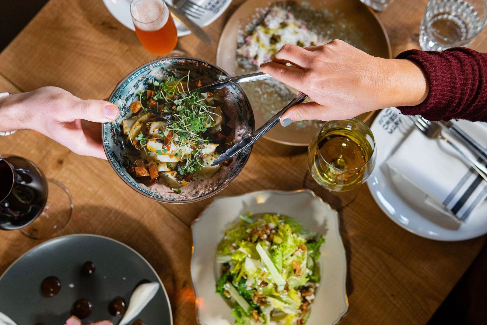 A table of shared dishes being passed between guests